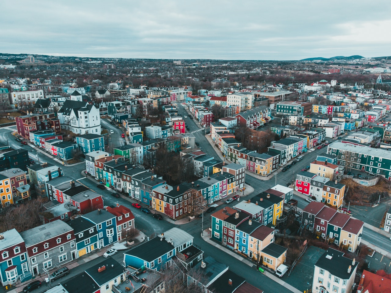 Aerial view of a colorful urban area with densely packed houses and streets, under a cloudy sky.