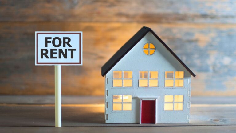 buying vs renting in michigan small home fo rent white siding red door windows on a wood grain backdrop